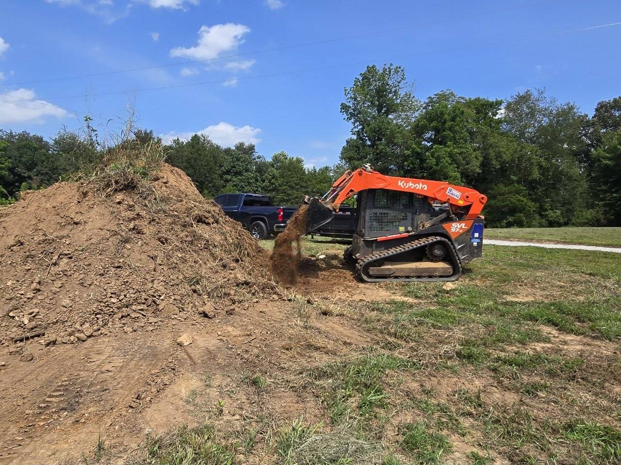Kubota SVL97-2 moving a pile of dirt in an open field