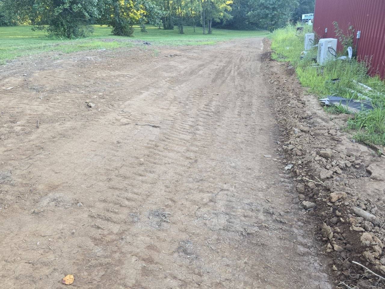 Finished drainage ditch sloped away from a building across a grassy yard