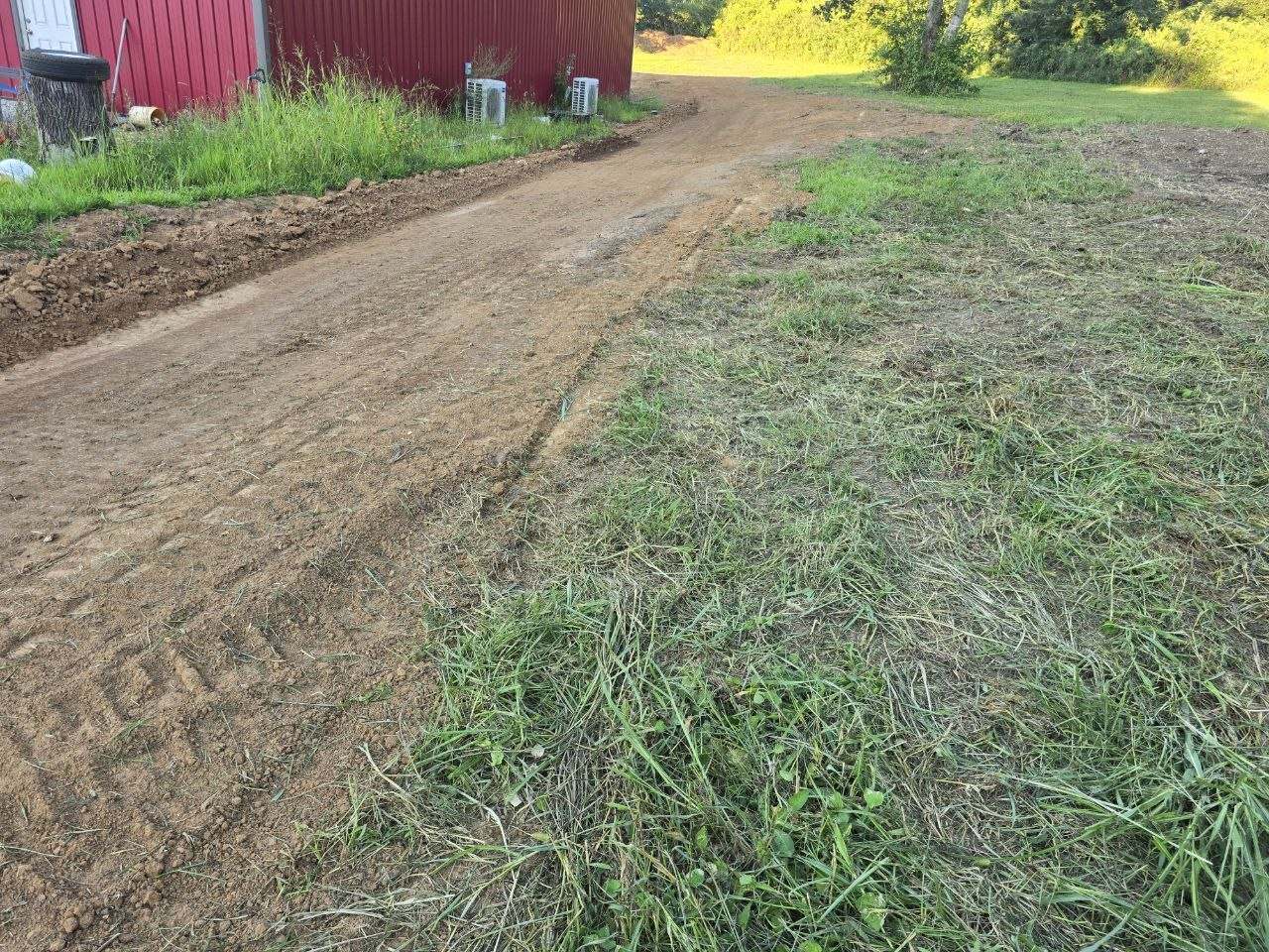 Freshly graded dirt lane beside a red barn