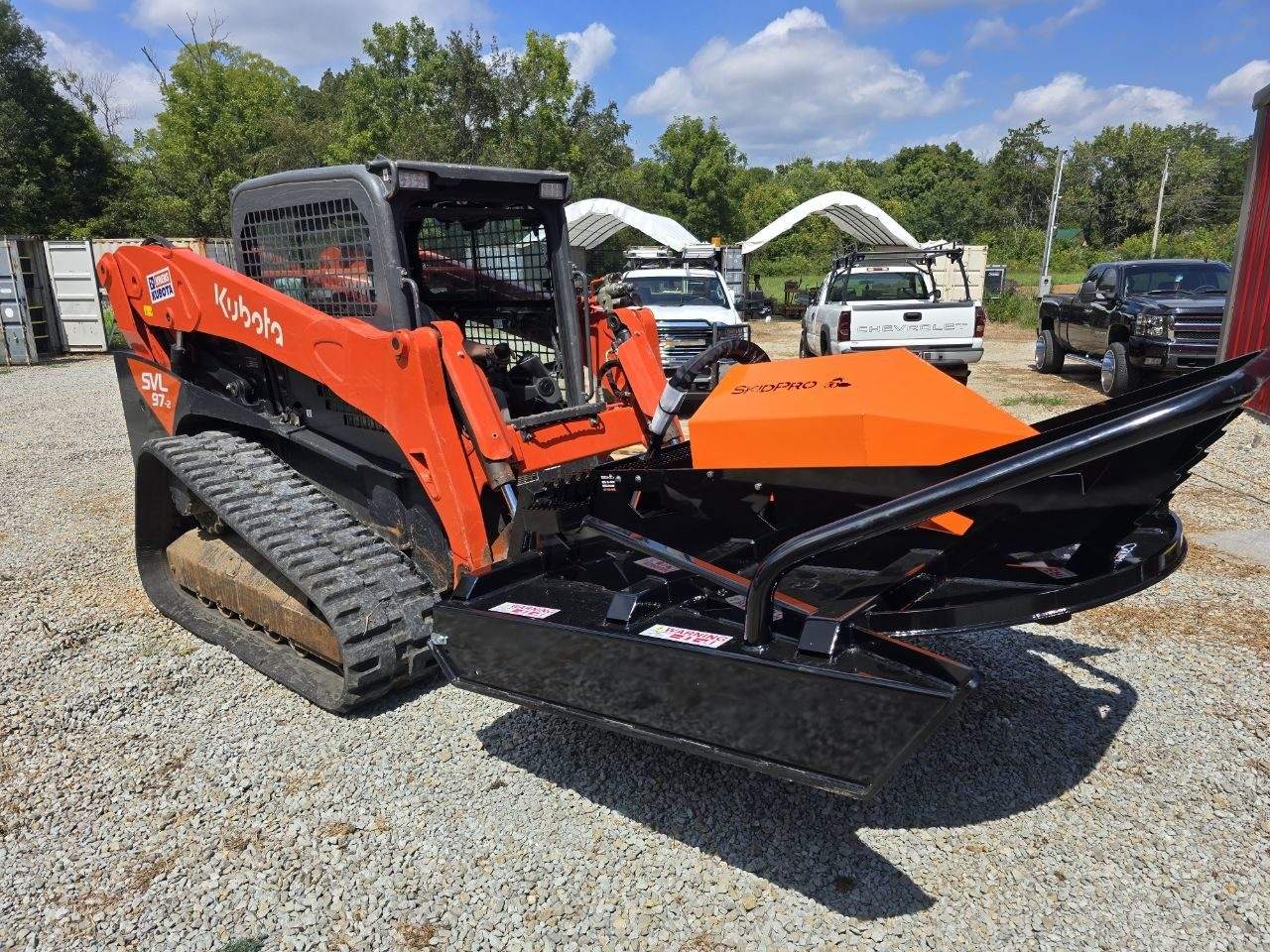 Kubota SVL 97-2 with a brush hog attachment parked on gravel