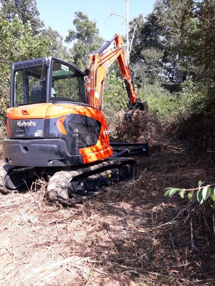 Kubota KX057-5 excavator working the next stump in the woods