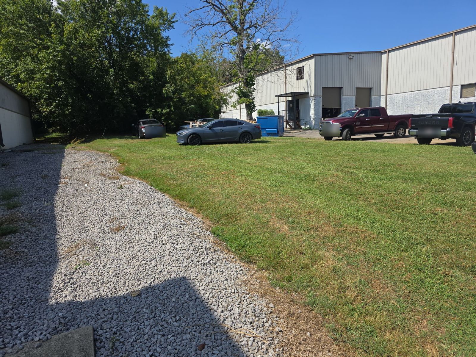 Before: grass strip behind a commercial building in La Vergne, TN, with trucks parked on the lawn