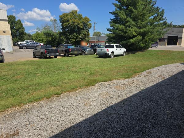 Before: pickup trucks parked on the grass strip behind the building