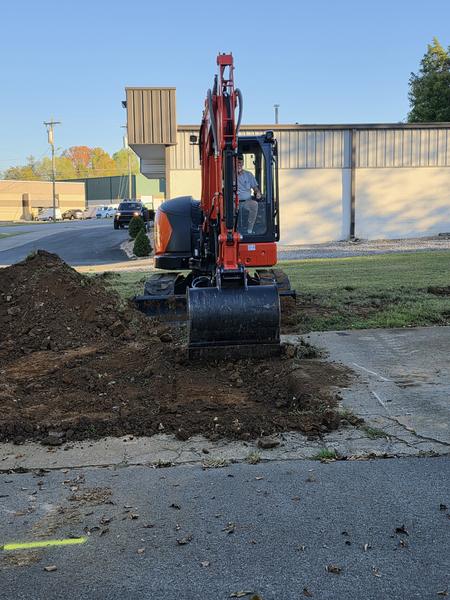 Front view of the Kubota KX057-5 with a pile of stripped topsoil