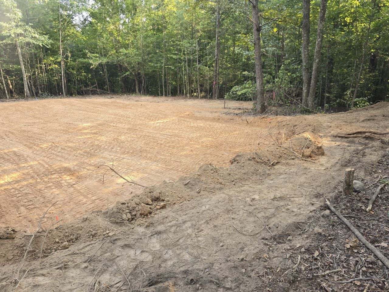 Flat packed pad with fine striped track marks and a small dirt berm in the foreground