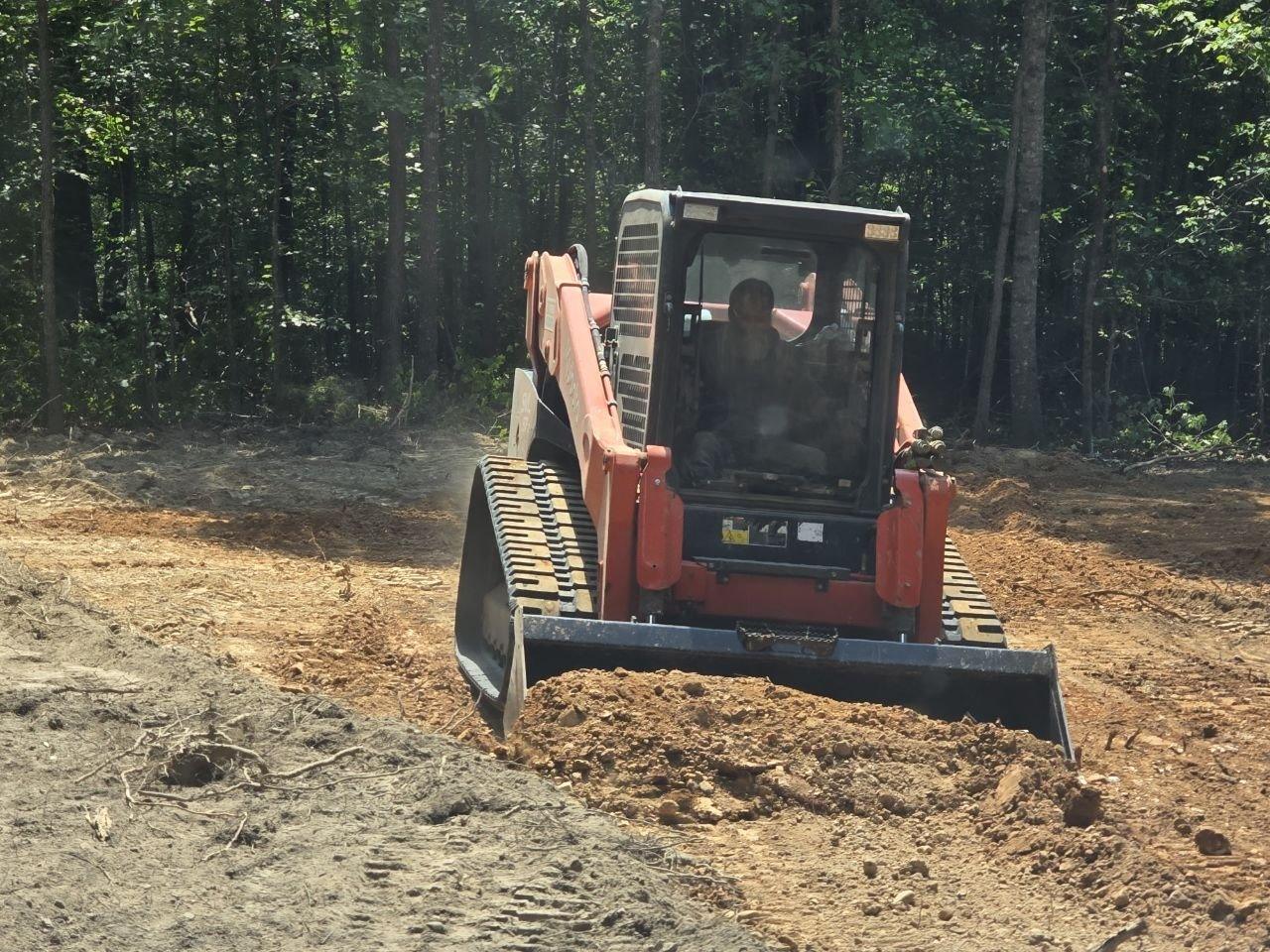 Orange Kubota SVL97-2 track loader pushing and leveling dirt on a building pad
