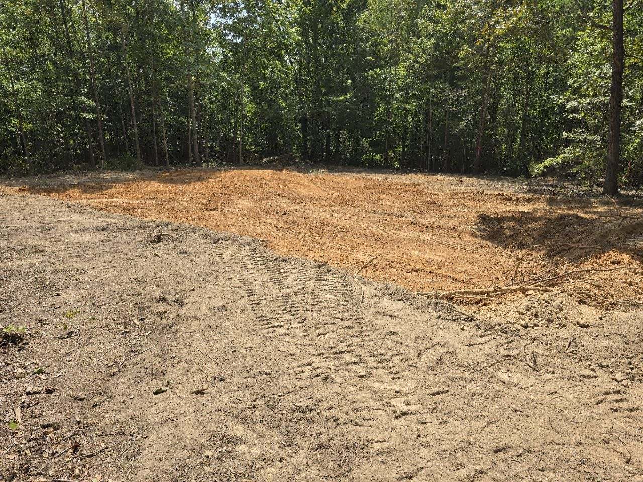 Large rectangular leveled pad with a packed clay center, surrounded by woods