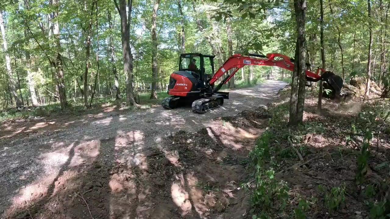 Kubota mini excavator working a drainage ditch beside a dirt road in Pulaski, TN