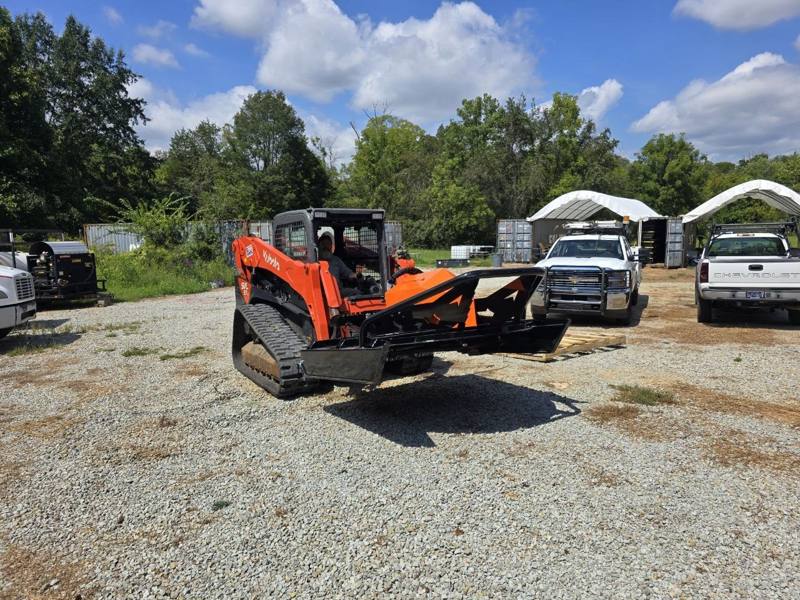 Skid steer with a brush hog attachment parked in the yard