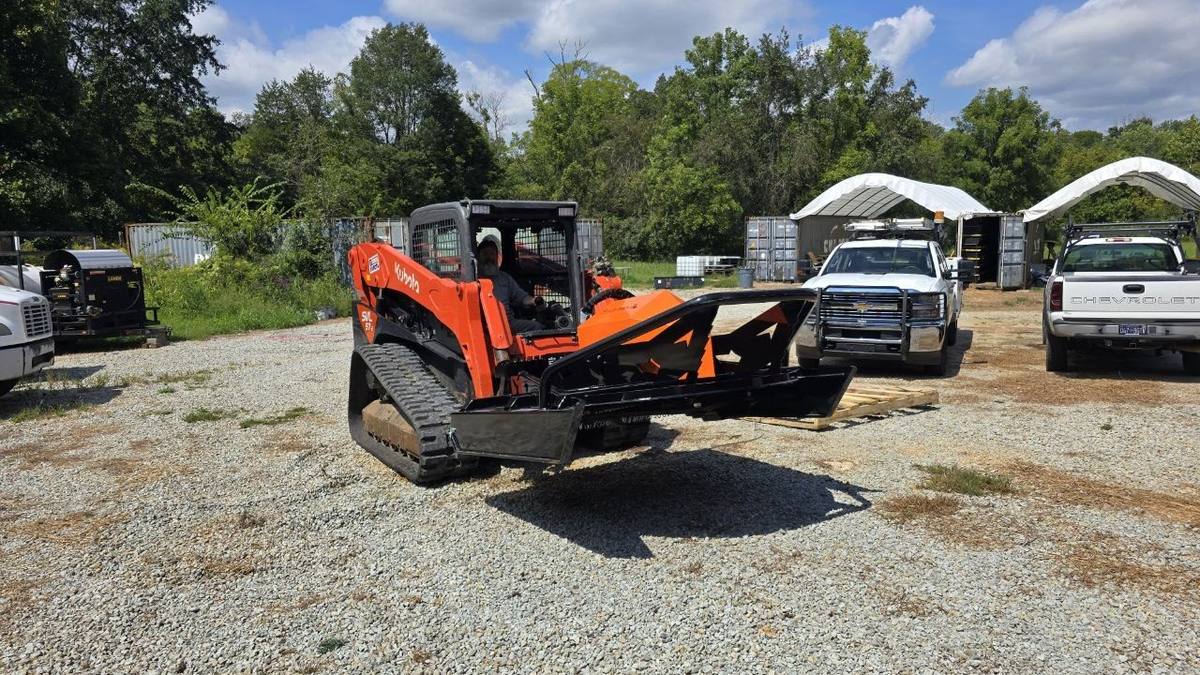 Orange Kubota SVL 97 track loader with a heavy-duty brush hog attachment parked on gravel